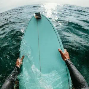 First person point of view photo of a surfer floating in the ocean while catching the waves on his surfboard